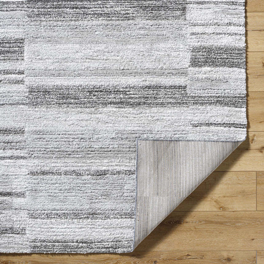 Close up of the Tayla Shag Area Rug. Light silver, sage, and silver gray shag rug with a horizontal striped pattern. Fold