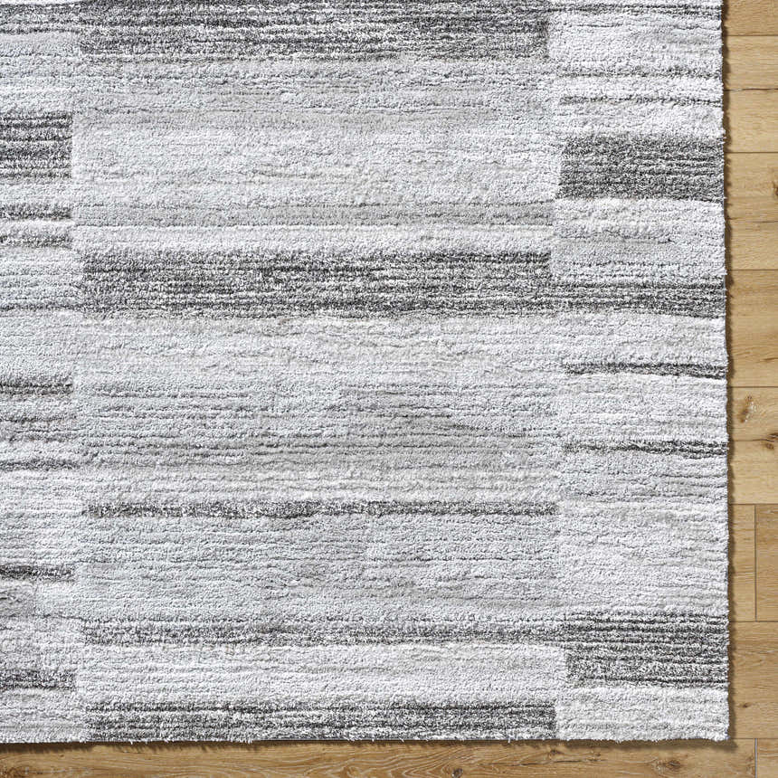 Close-up of the Tayla Shag Area Rug. Light silver, sage, and silver gray shag rug with a horizontal striped pattern. Corner