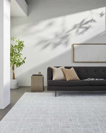 Living room scene with slate blue Telyn Area Rug, gray sofa, side table, and plant creating a contemporary, airy feel. Roomscene-Rectangle