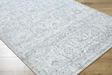 Close-up of Tariq area rug. Traditional floral pattern in silver gray, slate blue, and sterling gray on wood floor. Corner