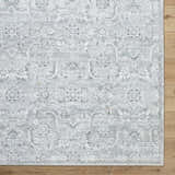 Close-up of the Tariq Area Rug. Silver gray, slate blue, and sterling gray traditional floral pattern. Machine woven. Corner
