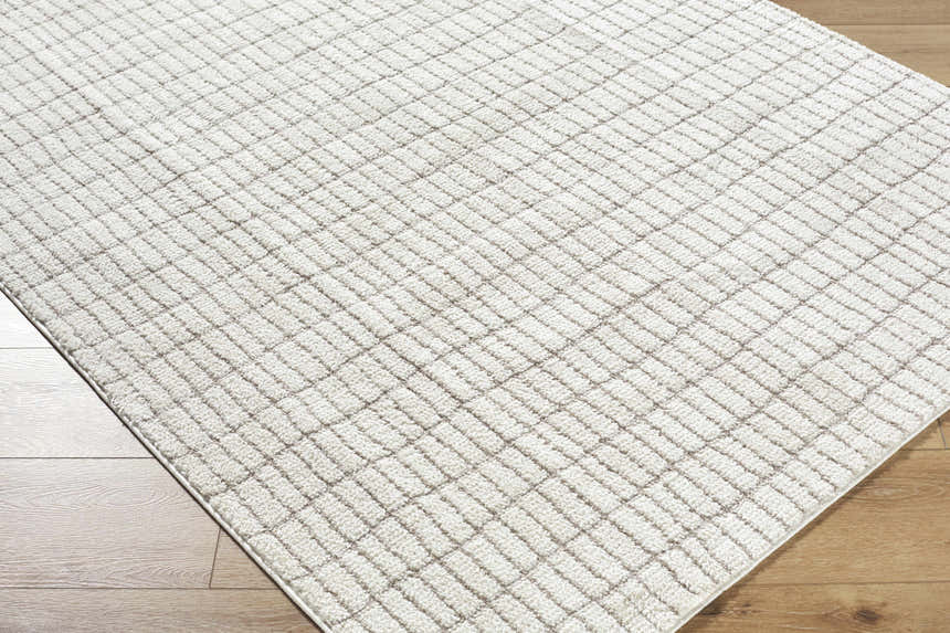 Close-up of the Cascade White Area Rug showing its ivory and taupe geometric pattern and soft, textured polyester pile. Corner
