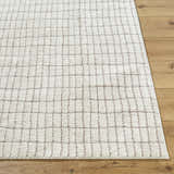 Close-up of the Cascade White Area Rug. Ivory polyester rug with a subtle taupe grid pattern on wood flooring. Front