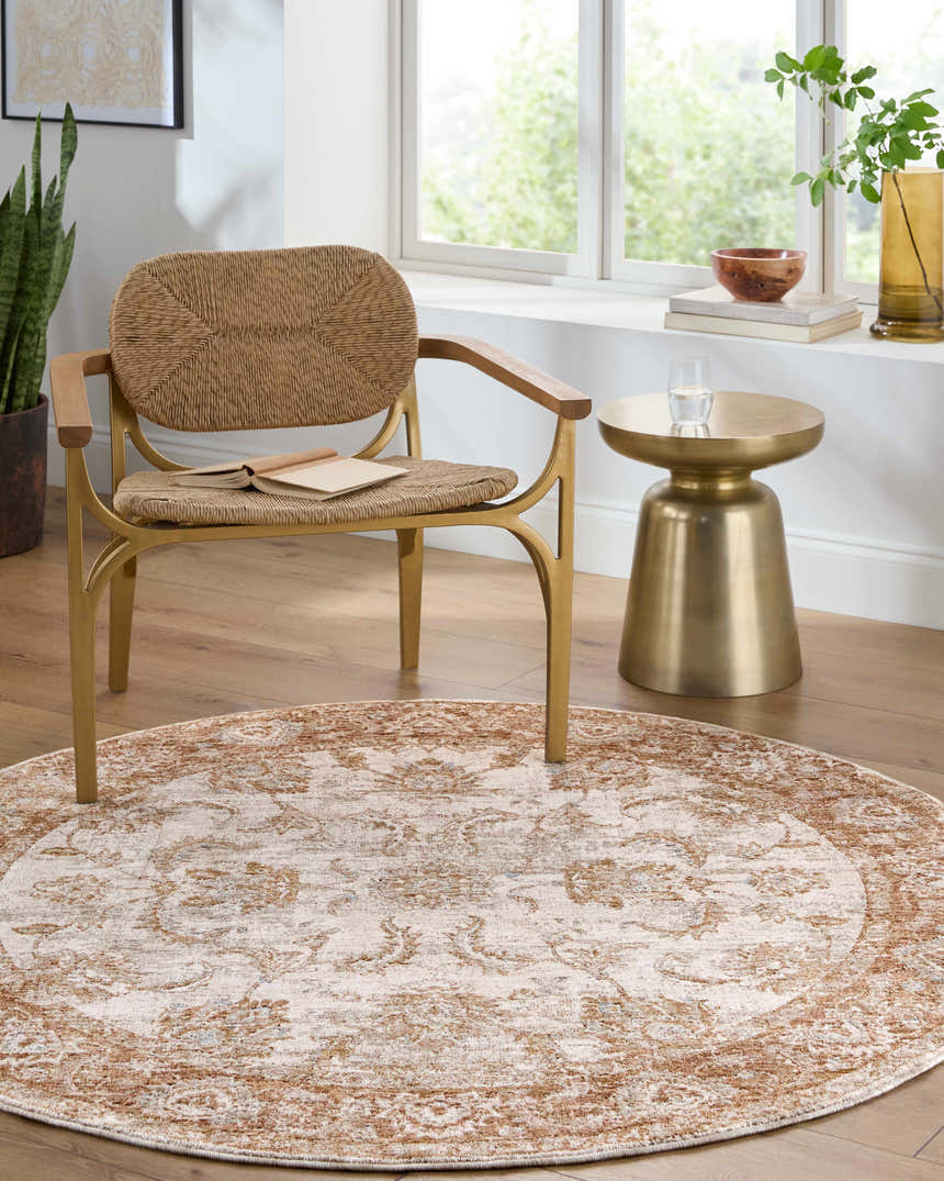 Light-filled room with a round Tylie Blue Area Rug, woven chair, gold side table, and wood floors. Roomscene-Round