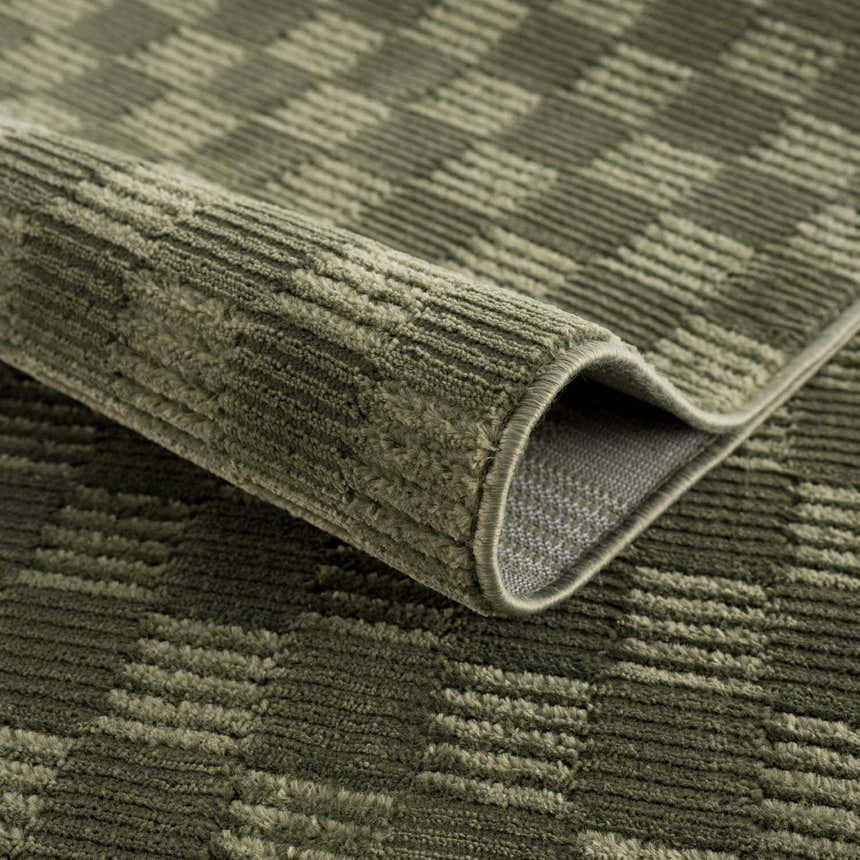Close-up of the green Truls 3D Checkered Washable Rug, showing the textured, checkered pattern and bound edge. Fold