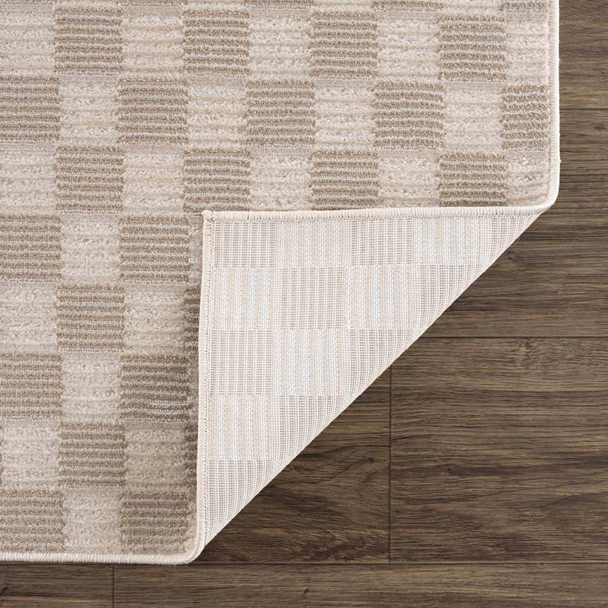 Close-up of Truls 3D Checkered Washable Rug in Biscotti. Beige and cream checkered pattern with a textured, machine-woven construction. Fold