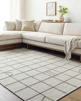 Living room with a Tieve Black & White Grid Wool Rug, cream sofa, and light wood accents. Roomscene-Rectangle