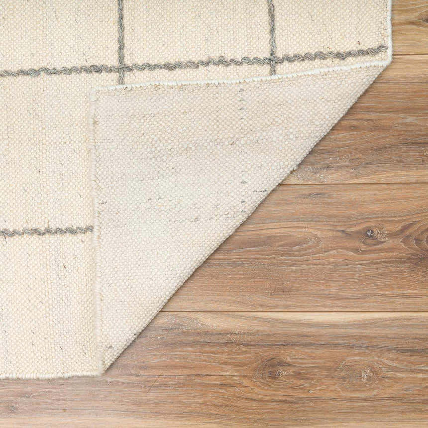 Close-up of Tieve Black & White Grid Wool Rug showing cream wool texture and gray grid pattern on wood floor. Fold