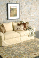 Living room scene with a Cherryfield Hand Tufted Taupe Wool Rug, cream sofa, stone wall, and floral pillows. Roomscene-Rectangle