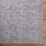 Close-up of the Telma Red Washable Area Rug, a traditional design in aqua, cream, red, and pink on a wood floor. Corner