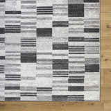 Close-up of the Tehya Gray Area Rug. Contemporary design with charcoal, silver gray, and slate blue blocks. Corner