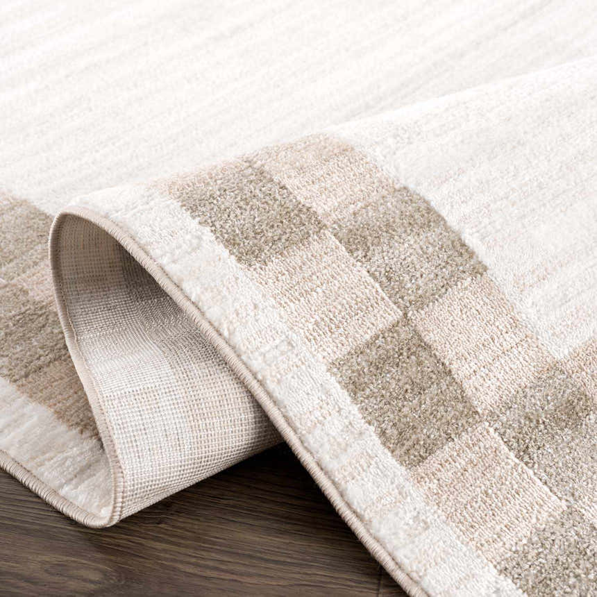Close-up of the Azrika Beige Checkered Washable Rug showing the geometric pattern and soft texture. Beige, dark brown, medium brown tones. Fold