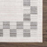 Close-up of the Azrika Gray Checkered Washable Rug. Beige, gray, and light gray checkered pattern. Machine woven texture. Swatch