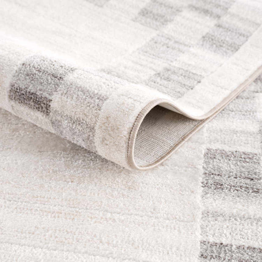Close-up of the Azrika Gray Checkered Washable Rug showing its beige, gray, and light gray geometric design and soft texture. Fold