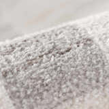 Close-up of the Azrika Gray Checkered Washable Rug. Soft, plush texture with a subtle beige and gray checkered pattern. Fold