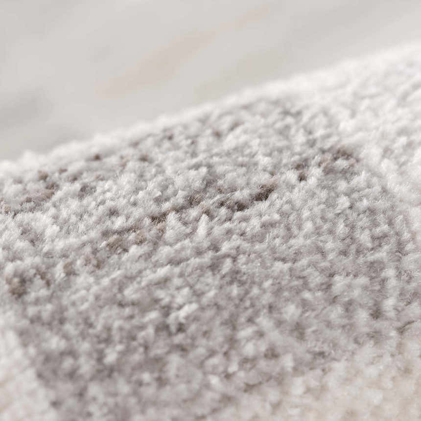 Close-up of the Azrika Gray Checkered Washable Rug. Soft, plush texture with a subtle beige and gray checkered pattern. Fold