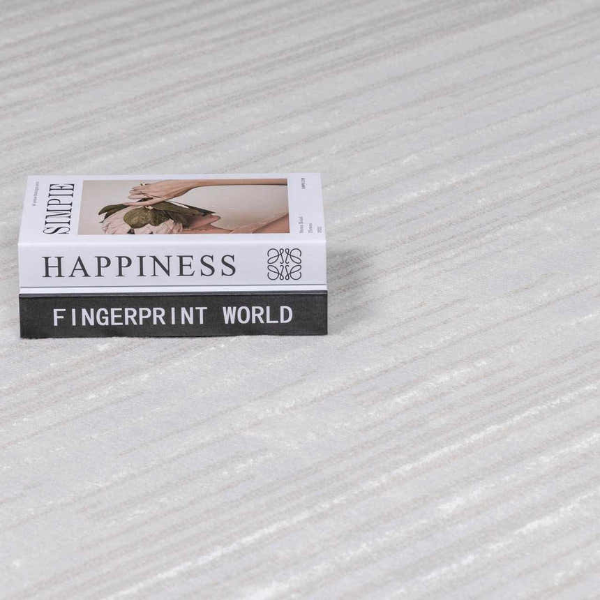 Close-up of the Azrika Gray Checkered Washable Rug with beige and gray tones and a stack of decorative books. Styleshot