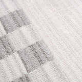 Close-up of the Azrika Gray Checkered Washable Rug. Beige, gray, and light gray geometric pattern. Soft, textured polyester. Texture