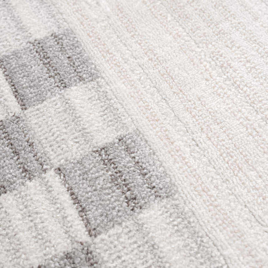 Close-up of the Azrika Gray Checkered Washable Rug. Beige, gray, and light gray geometric pattern. Soft, textured polyester. Texture