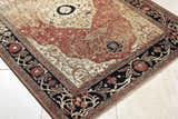 Close-up of the Vonda Area Rug. Traditional design in charcoal, crimson, gold, and ivory. Floral border detail. Corner