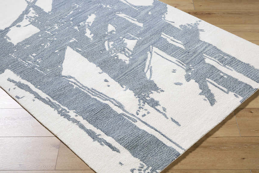 Close-up of the hand-tufted Viven Slate Blue Area Rug. Contemporary wool rug with a white and slate blue abstract pattern. Corner