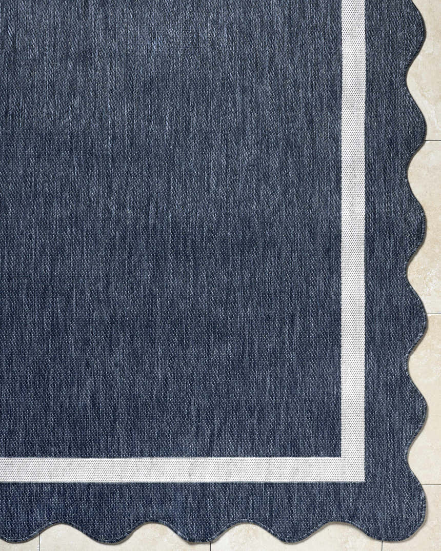 Close up of Varro Navy Area Rug showing texture, cream border, and scalloped edge. Corner