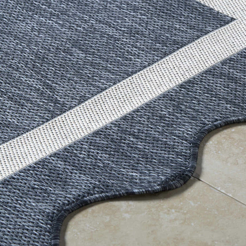 Close-up of the Varro Navy Area Rug showing its woven texture, cream stripe detail, and scalloped edge. Texture