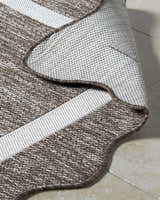 Close-up of Varro Dark Brown Area Rug showing cream and dark brown woven texture and bound edge. Fold