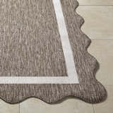 Close-up of the Varro Dark Brown Area Rug showing its woven texture, cream border, and unique scalloped edge. Front