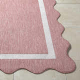 Close-up of the Varro Dark Pink Area Rug showing its cream border and unique scalloped edge detail. Front