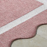 Close-up of the Varro Dark Pink Area Rug showing its woven texture, cream stripe, and scalloped edge. Texture