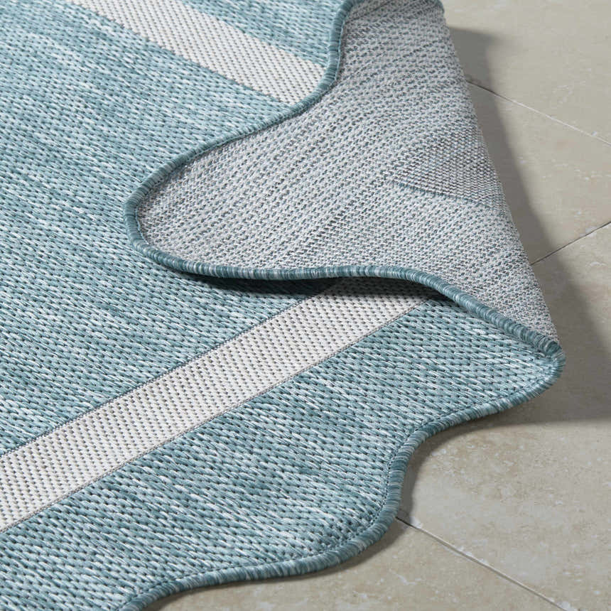 Close-up of the Varro Aqua Area Rug showing the aqua and cream woven texture and bound edge. Fold