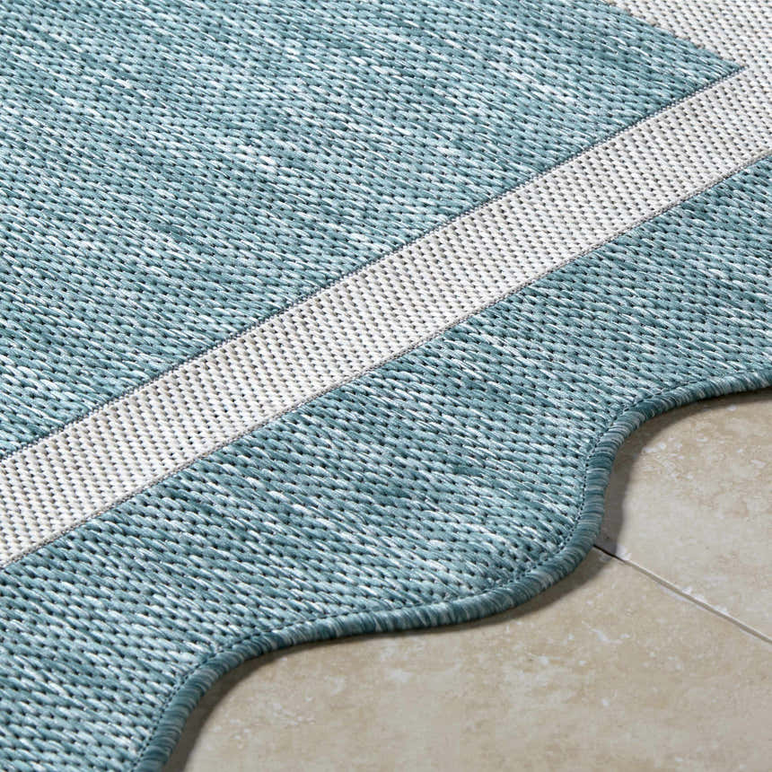 Close-up of Varro Aqua Area Rug showing aqua and cream colors, woven texture, and scalloped edge. Texture