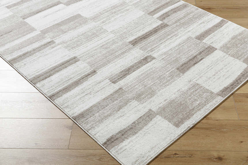 Close-up of the Vasso Beige Area Rug, a contemporary rug with a geometric block pattern in light silver and warm gray tones. Corner