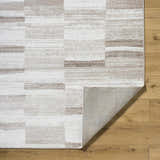 Close up of the Vasso Beige Area Rug showing a contemporary geometric pattern in silver, gray, and beige tones. Fold