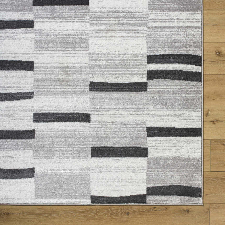 Close-up of the Vasso Gray Area Rug. Contemporary design with ink, silver gray, and light silver blocks. Machine woven texture. Corner