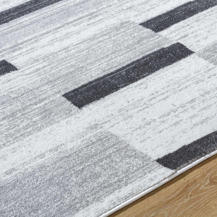 Close-up of the Vasso Gray Area Rug. Features an abstract geometric pattern in ink, light silver, and silver gray hues. Texture