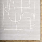 Close-up of the Vatsa Gray Abstract Area Rug. Light silver wool rug with a raised, geometric white line pattern. Swatch