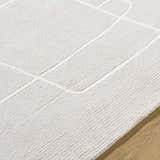 Close-up of the Vatsa Gray Abstract Area Rug, a hand-tufted wool rug with a geometric design in light silver and sterling gray. Texture