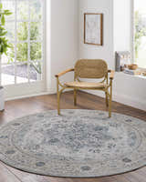 Light-filled room with round Whangamata Thick Luxe Boutique Rug, woven chair, and wood floors. The rug features a traditional, oriental pattern. Roomscene-Round