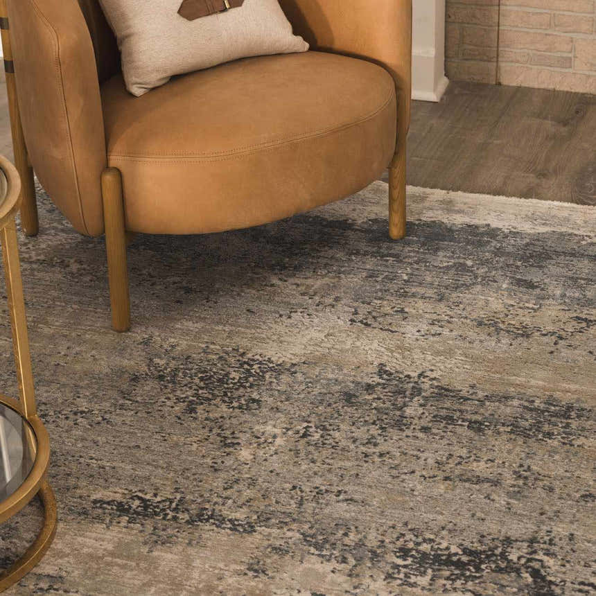 Close-up of the Whyalla Misty Thick Luxe Rug with a tan and gray abstract pattern, styled with a leather chair. Styleshot