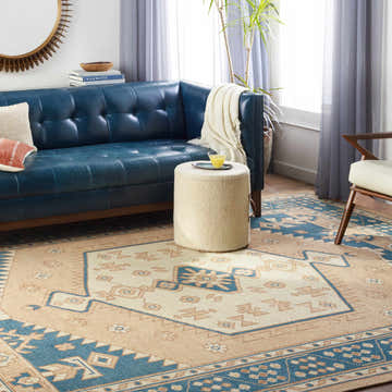 Living room with a blue leather couch and the beige and blue Wilbraham Area Rug. Roomscene-Rectangle