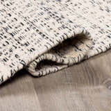 Close-up of the hand-woven Williford Wool Area Rug. Cream wool with black stripes and a visible, textured weave. Fold