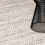 Close-up of the cream and black Williford Wool Area Rug, hand woven texture, with a black wire side table. Styleshot