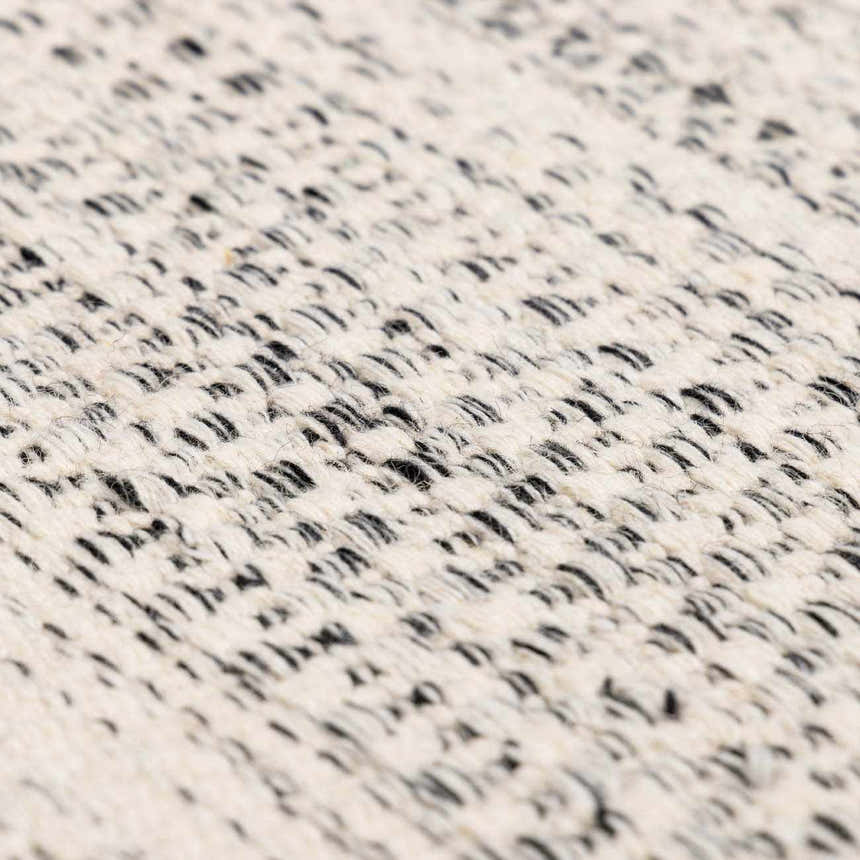 Close-up of the hand-woven Williford Wool Area Rug. Cream rug with a subtle black striped pattern and textured wool fibers. Texture