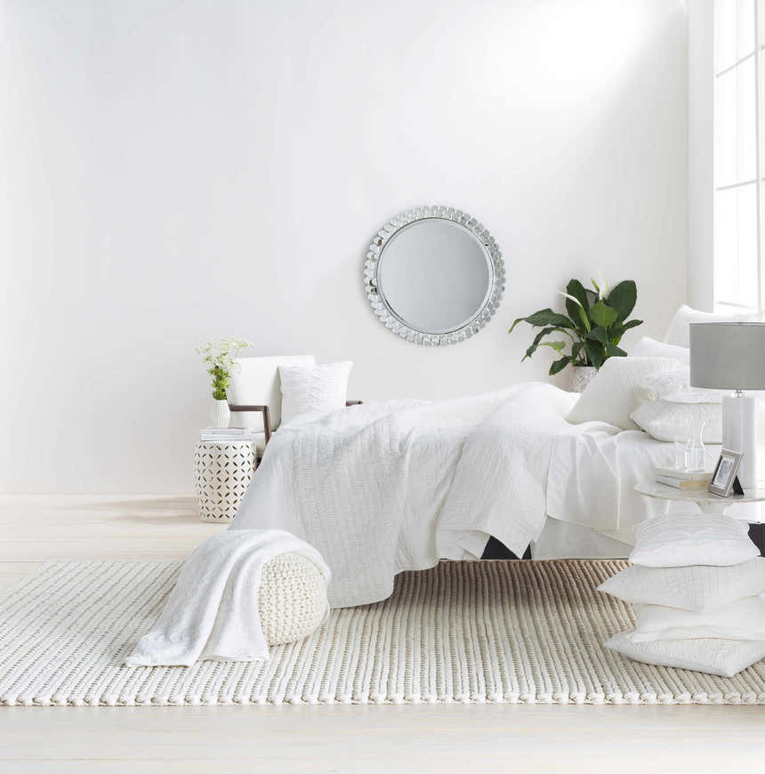 Bright bedroom scene with a cream Christoval Area Rug, white bedding, and natural light. Roomscene-Rectangle