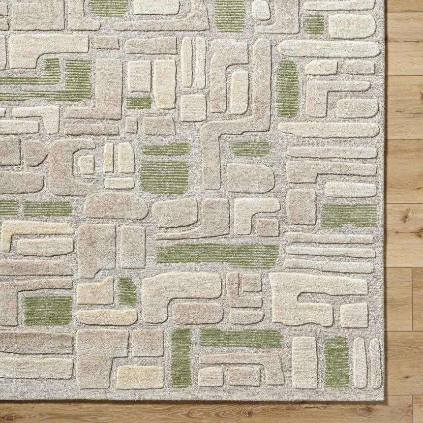 Close-up of the Alaqua Area Rug. Hand-tufted wool rug in ash, desert sand, and slate blue with a contemporary geometric pattern. Corner