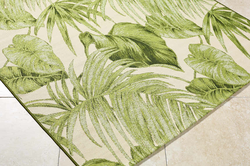 Close-up of Amirah Green Area Rug with olive and ivory tropical leaf pattern. Machine woven texture. Coastal style rug. Corner