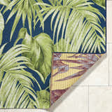 Close-up of the Amirah Teal Area Rug showing its tropical leaf pattern, teal background, and the rug's underside. Fold