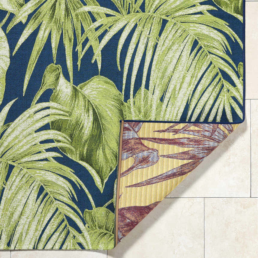 Close-up of the Amirah Teal Area Rug showing its tropical leaf pattern, teal background, and the rug's underside. Fold